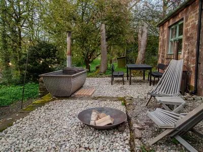 a backyard with a fire pit and a grill and chairs at Stable Cottage, Gartocharn, Loch Lomond in Alexandria