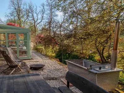 a garden with a bench and a greenhouse at Stable Cottage, Gartocharn, Loch Lomond in Alexandria