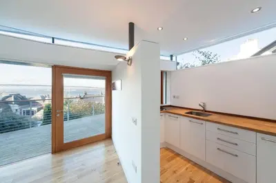 a kitchen with white cabinets and a large window at The Nook, Studio Apartment, South Queensferry in Queensferry