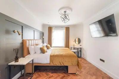 a bedroom with a bed with a desk and a television at King Street Aparthotel in Stirling