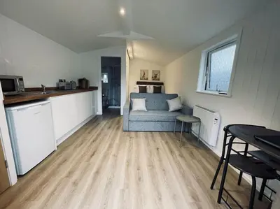 a living room with a blue couch and a kitchen at West Highland Snug in Kinlochleven