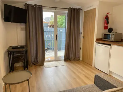 a living room with a kitchen and a door to a balcony at West Highland Snug in Kinlochleven