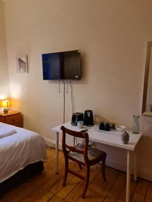 a room with a bed and a table with a television on the wall at Haymarket Station Rooms in Edinburgh