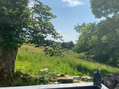 a stone bench in a field with a tree at Lovely new caravan by Loch Long in Cove