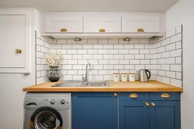 a kitchen with blue cabinets and a washing machine at The Riverside Hideaway by Calton Living in Edinburgh