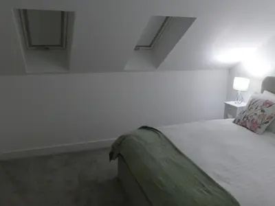 a white bedroom with a bed and a lamp at The Annexe in Eaglesham