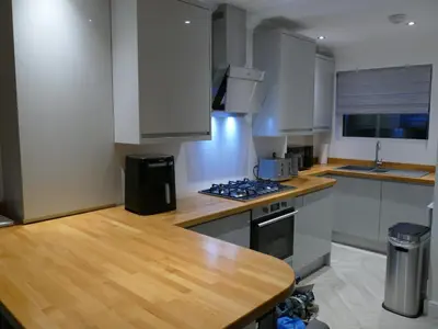 a kitchen with white cabinets and a wooden counter top at The Annexe in Eaglesham