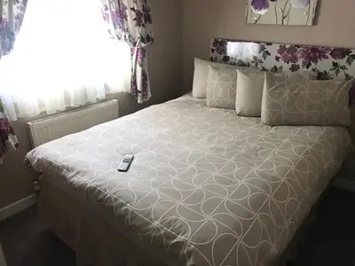 a bed with a remote control sitting on top of it at Red Deer Village Holiday Park - 3 Bedroom, Self-Catering Holiday Home in Steps