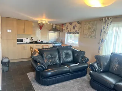a living room with two leather couches and a kitchen at Red Deer Village Holiday Park - 3 Bedroom, Self-Catering Chalet in Steps