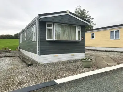 a black and white tiny house in a yard at Red Deer Village Holiday Park - 3 Bedroom, Self Catering Static Caravan in Steps