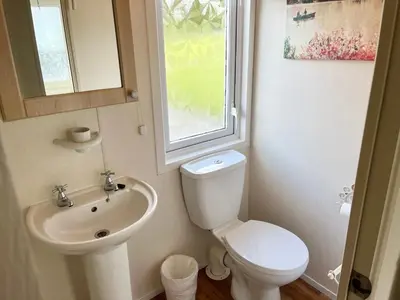 a bathroom with a sink and a toilet and a window at Red Deer Village Holiday Park - 3 Bedroom, Self Catering Static Caravan in Steps