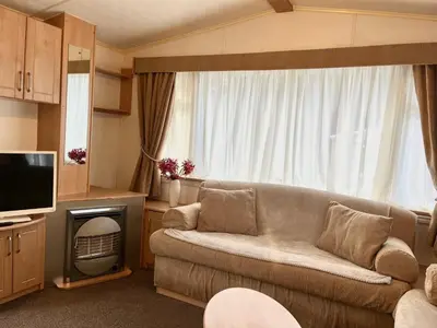 a living room with a couch and a television at Red Deer Village Holiday Park - 3 Bedroom, Self Catering Static Caravan in Steps