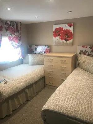 a bedroom with two twin beds and a dresser at Red Deer Village Holiday Park - 2 Bedroom, Self-Catering Chalet in Steps