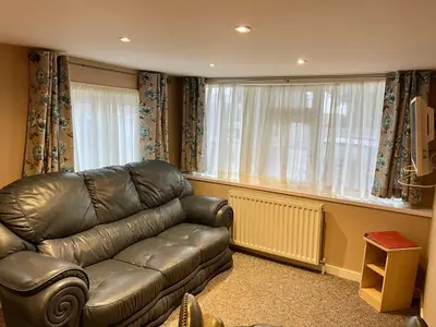 a living room with a leather couch and a large window at Red Deer Village Holiday Park - 2 Bedroom, Self-Catering Chalet in Steps