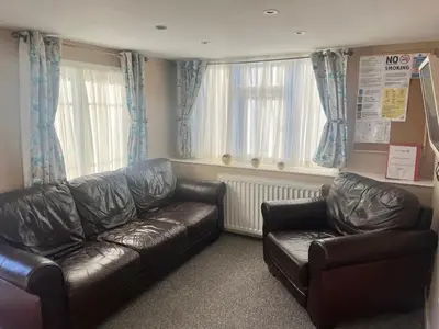 a living room with two leather couches and windows at Red Deer Village Holiday Park - 2 Bedroom, Self-Catering Chalet in Steps