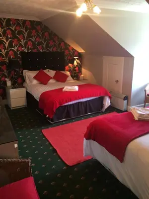 a hotel room with two beds with red sheets at Broom Lodge in Largs
