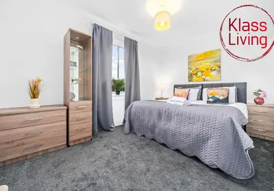 a bedroom with a king sized bed and a dresser at Broomfield Apartment by Klass Living Airdrie in Airdrie
