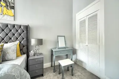 a bedroom with a bed and a table with a mirror at Two Bed Stylish Apartment in Heart of West End in Glasgow