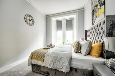 a white bedroom with a large bed with yellow pillows at Two Bed Stylish Apartment in Heart of West End in Glasgow