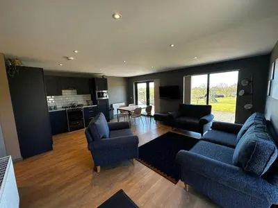 a living room with two blue couches and a kitchen at Spacious 3-Bedroom Chalet on Country Estate near Glasgow - sleeps 6 in Glasgow