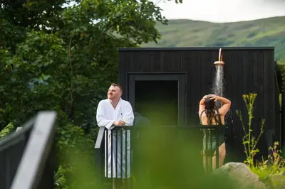 a man standing in front of a black building at Forest Corner Luxury Apartment with Hot Tub in North Ballachulish