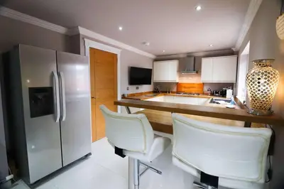 a kitchen with two white chairs and a refrigerator at Woodhead view in Kirkintilloch