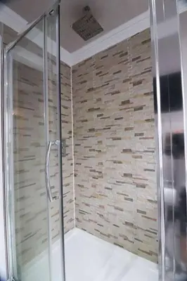 a shower in a bathroom with a stone wall at Woodhead view in Kirkintilloch