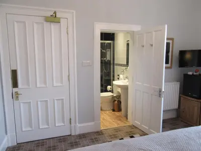 a bedroom with a door leading to a bathroom at Middleton House Bed and Breakfast in Auchterarder