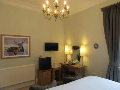 a bedroom with a bed and a desk and a television at Middleton House Bed and Breakfast in Auchterarder