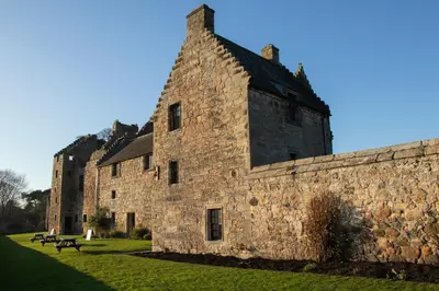 an old stone building with a stone wall at Seaside Place, Aberdour in Aberdour