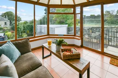 a living room with a couch and a table at Blacksands Seaview Cottage, Aberdour in Aberdour