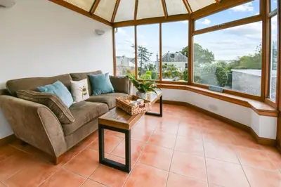 a living room with a couch and large windows at Blacksands Seaview Cottage, Aberdour in Aberdour