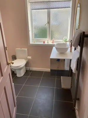 a bathroom with a toilet and a sink and a window at Blacksands Seaview Cottage, Aberdour in Aberdour