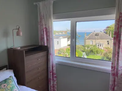 a bedroom with a window with a view of the ocean at Blacksands Seaview Cottage, Aberdour in Aberdour