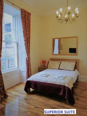 a bedroom with a bed with a mirror and a window at Edinburgh City Suites in Edinburgh