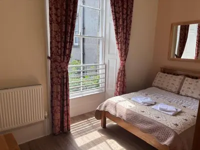 a bedroom with a bed and a large window at Edinburgh City Suites in Edinburgh