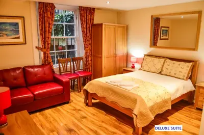 a bedroom with a bed and a couch and a chair at Edinburgh City Suites in Edinburgh