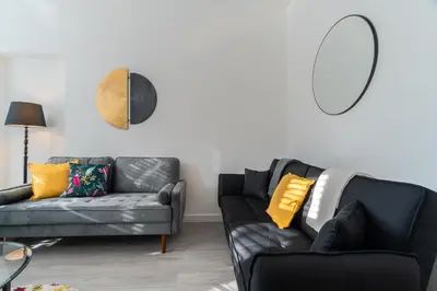 a living room with a black couch and yellow pillows at Dyke Apartment in Bailleston