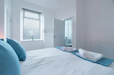 a white bed with blue pillows and towels on it at Dyke Apartment in Bailleston