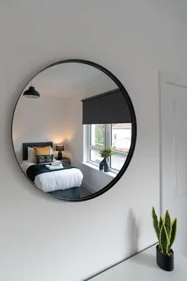 a mirror in a bedroom with a bed and a window at Locksley House in Knightswood