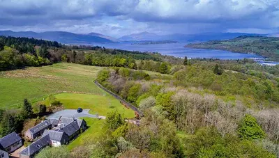 an aerial view of a house on a hill with a lake at Sheildaig Farm in Balloch