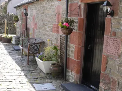 an alley with a bench and potted plants next to a building at Sheildaig Farm in Balloch