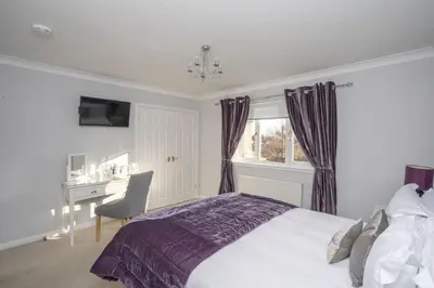 a bedroom with a bed and a desk and a window at Springfield Lodge Bed and Breakfast in Stirling