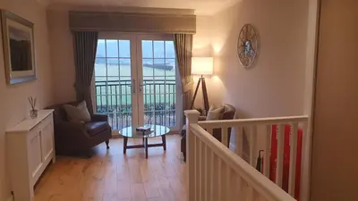 a living room with a staircase with a chair and a table at Springfield Lodge Bed and Breakfast in Stirling