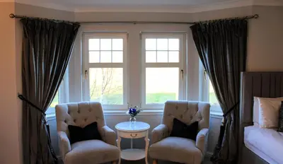 two chairs and a table in a room with a window at Springfield Lodge Bed and Breakfast in Stirling