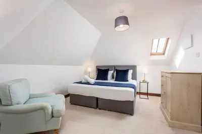 a bedroom with a bed and a chair at Cromwell Corner - Donnini Apartments in Ayr