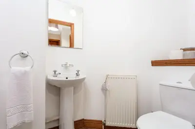 a white bathroom with a sink and a toilet at Cromwell Corner - Donnini Apartments in Ayr