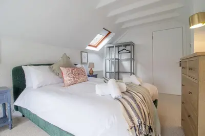 a bedroom with a large white bed and a dresser at Henry Bell - Cosy 2-bedroom cottage in Helensburgh