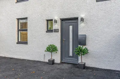 a house with two plants in front of a door at Parkside 2 bedroom house near Dunfermline & Edinburgh in Dunfermline