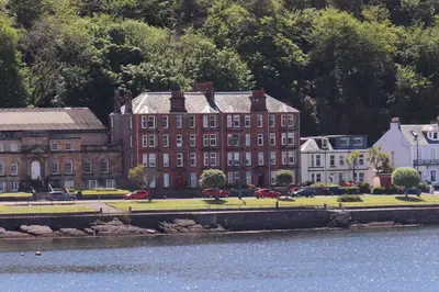 a large brick building next to a body of water at Bellevue Bute, Luxury 2 bedroom sea view flat in Rothesay